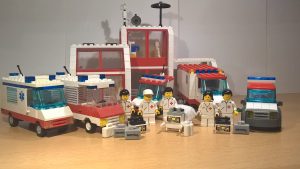 LEGO® Rettungsdiensteinheiten stehen mit ihren Fahrzeugen und Ausrüstung vor dem Krankenhaus